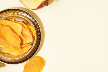 Plate with slices of dried mango on yellow background