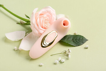 Vibrator with flowers on green background, closeup