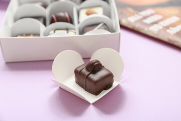 Box with delicious candies on purple background