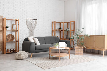 Beautiful interior of living room with black sofa, chest of drawers, coffee table and olive tree