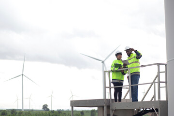 Two engineer check and examining wind turbines in wind farm, renewable energy and teamwork in a...