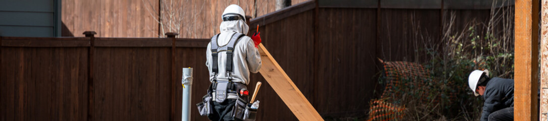 Construction worker, carpenter, in tool belt and hard hat on housing development project,...