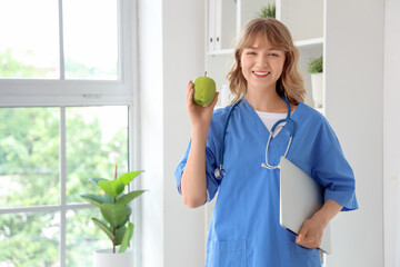 Female nutritionist with apple and laptop in office