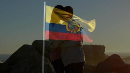 Embracing on rocky shore, couple with Ecuador flag waving above them - Powered by Adobe