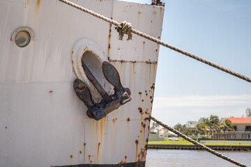 Ancla y proa de barco oxidado con fondo de cielo azul y casa grande