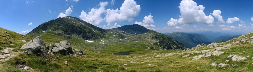 Fototapeta premium A breathtaking mountain range towers majestically in the background, framed by lush green grass in the valley below. A serene, sparkling lake reflects the stunning peaks, creating a picturesque scene.