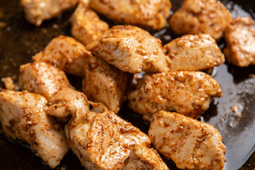 Chicken pieces are fried in a frying pan in sauce and spices.