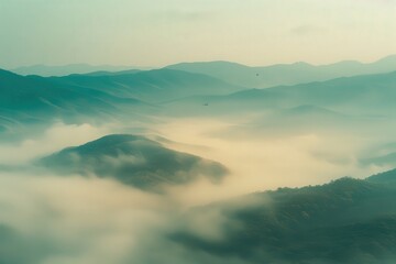 Fototapeta premium Misty mountains create a serene and ethereal landscape, with layers of hills shrouded in fog under soft lighting.
