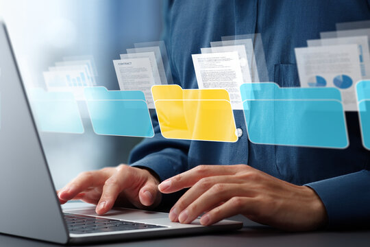 Document management system DMS and automated classification technology. Text documents and folder icons. Businessman using laptop computer for tagging and retrieving digital documents.