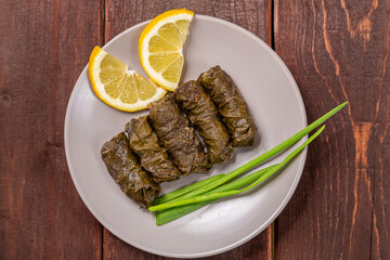 Dolma homemade with meat in grape leaves on a plate decorated with lemon