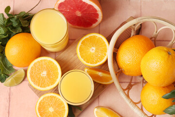 Wooden board with glasses of tasty juice, oranges and mint leaves on beige tile background