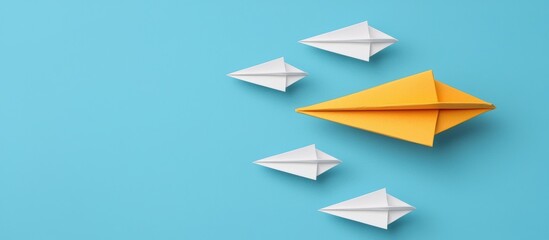 Fototapeta premium Yellow Paper Airplane Leading White Formation Against Clear Blue Background
