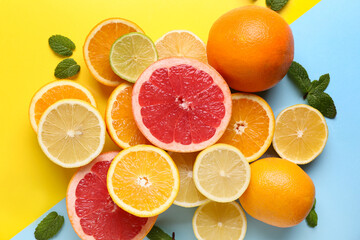 Different cut citrus fruits with mint leaves on color background