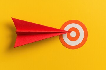 Red Paper Airplane Aiming at Target on Bright Yellow Background Symbolizing Focus and Achievement