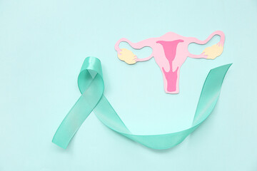 Turquoise ribbon with paper uterus on blue background. Cervical Health Awareness Month