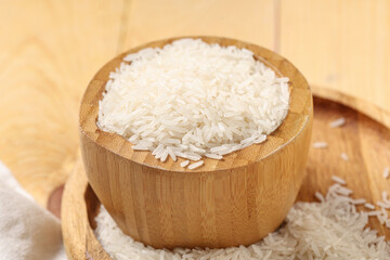 Bowl of raw rice on wooden background
