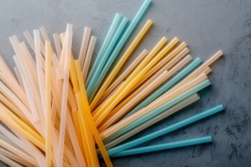 Obraz premium A colorful assortment of plastic drinking straws scattered on a textured gray surface, showcasing various lengths and shades.