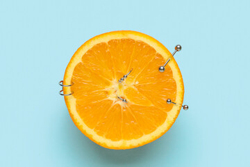 Half of orange fruit with piercing on blue background