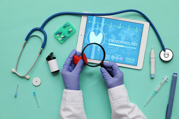 Doctor holding thyroid gland model with magnifier and medical supplies on green background....