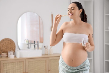 Pregnant woman brushing teeth in bathroom