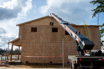 Heavy duty work truck with conveyer belt boom arm delivering roofing materials to a residential...
