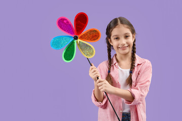 Cute girl with toy windmill on lilac background