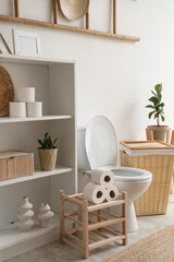 Interior of light restroom with toilet bowl, shelf unit and basket
