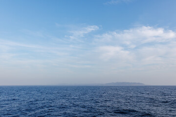 Fototapeta premium 夕日に染まる房総半島。 白い灯台や漁船も見える。 東京湾から眺める美しい夕陽。 東海汽船東京湾～伊豆諸島八丈島、太平洋航路の橘丸船上にて - 2025 