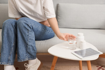 Young woman with menstrual cramps going to take antispasmodic drugs at home