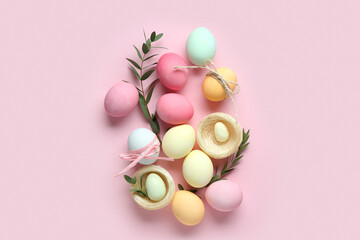 Composition with Easter eggs, decorative nests and green twigs on pink background