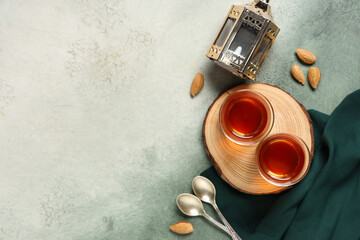 Glasses of tasty Turkish tea with nuts and fanoos on grey grunge background. Ramadan celebration