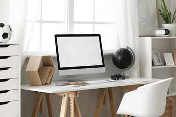 Teenager's workplace with blank computer monitor near window in room