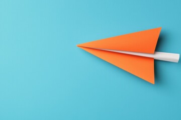 Fototapeta premium Vibrant Orange Paper Airplane Gliding Against a Bright Blue Background Symbolizing Freedom And Creativity