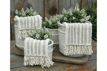 Fototapeta premium Charming decorative pots filled with greenery, adorned with textured fabric accents, set against a rustic wooden backdrop.