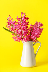Vase with beautiful pink hyacinth flowers on yellow background