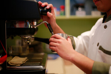 Barista heats milk to prepare a cappuccino