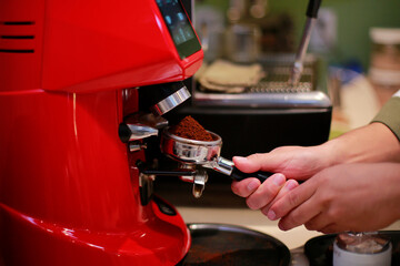 Barista uses a coffee grinder to prepare an espresso