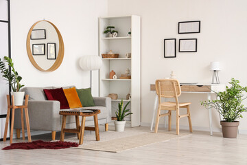 Interior of light living room with grey sofa, workplace and mirror