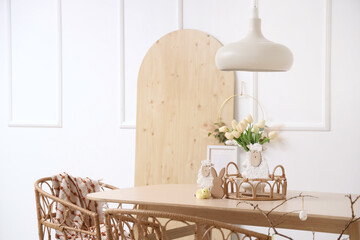 Interior of festive dining room with wooden board, Easter decorations and tulip flowers on big table