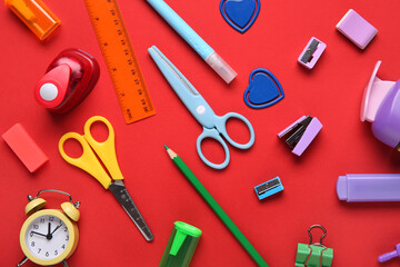Set of school stationery with alarm clock on red background