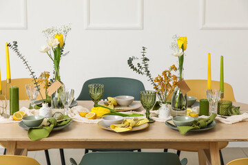Table setting with spring flowers near light wall in room