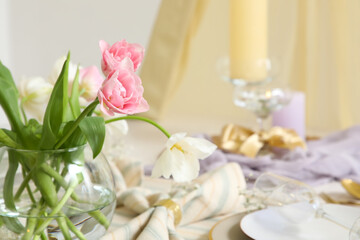 Vase with tulips on dining table in room, closeup