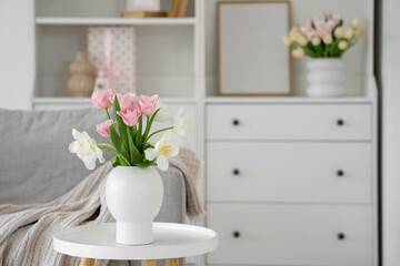 Vase with flowers on table in living room decorated for Mother's Day