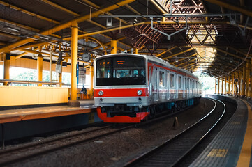 Fototapeta premium the commuter city train slowly entered the station, The train has multiple passenger cars.&nbsp;The train is on a railway track that runs along the platform.&nbsp;Tracks run parallel to one another.&nbsp;