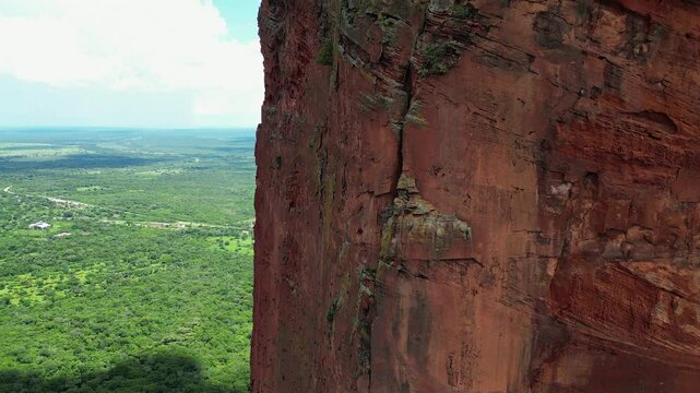 Aerial rises up vertical red stone cliff of Torre de David in Bolivia