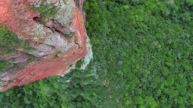 Perspective aerial looks directly down sandstone cliff on stone pillar