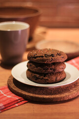 Handmade cookies with chocolate chips on a white plate and fresh milk in a glass. Selective focus