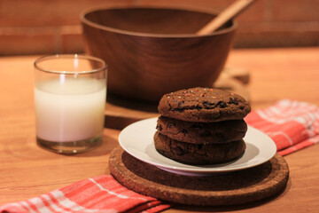 Handmade cookies with chocolate chips on a white plate and fresh milk in a glass. Selective focus