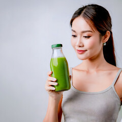Beautiful woman holding a glass of green healthy smoothie on a light grey background. Healthy eating and diet.