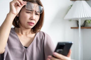 asian woman, 45 years old, experiencing eyesight problems due to farsightedness, trying to read...